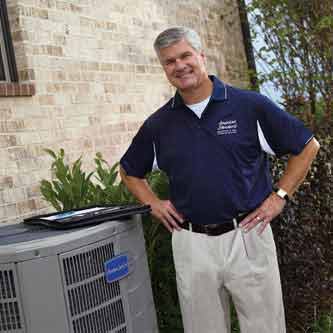 hvac tech standing by air conditioner